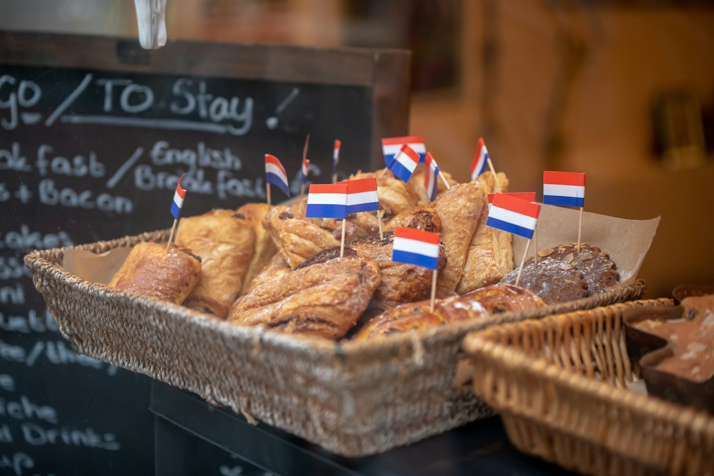 Assorted Dutch pastries in a wicker basket on a bakery counter.