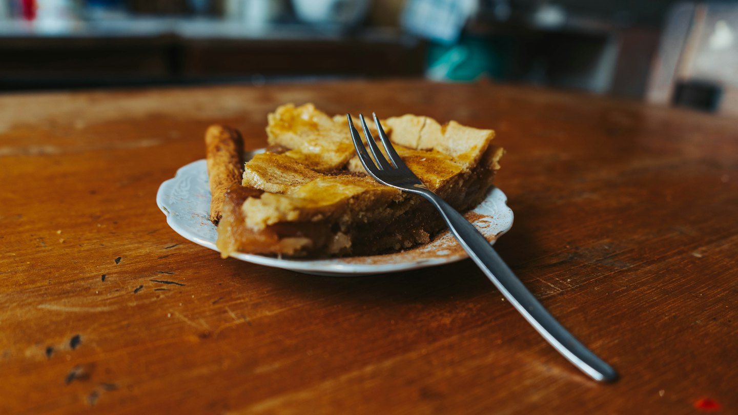 Slices of apple pie with a fork on a wooden table.